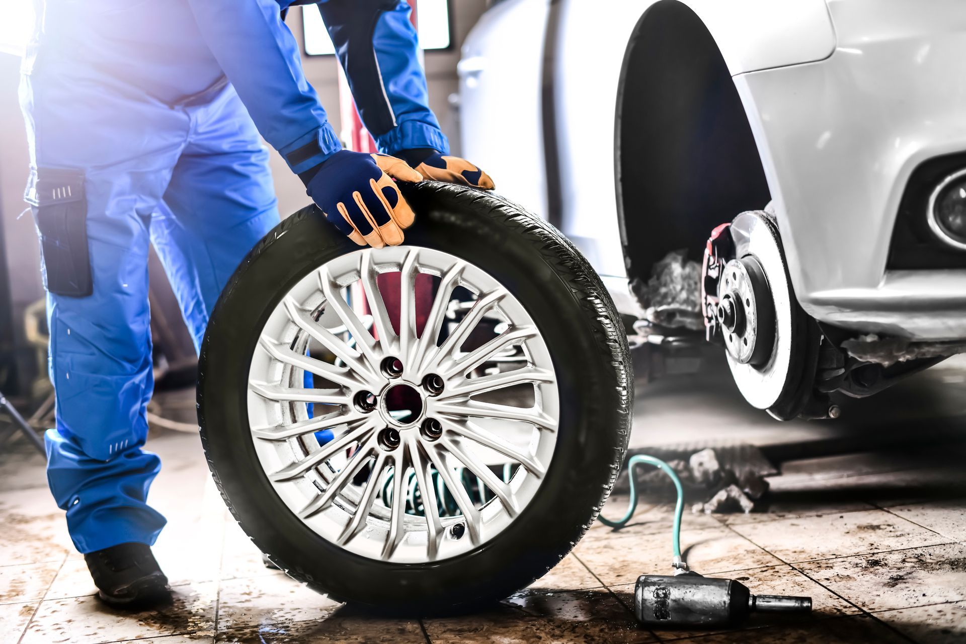 An auto mechanic working in a garage and changing a wheel alloy tire.