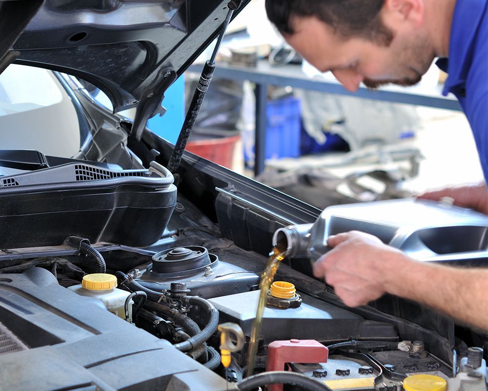 An AMSOIL oil change technician from Professional Automotive providing an oil change on a car in Anc