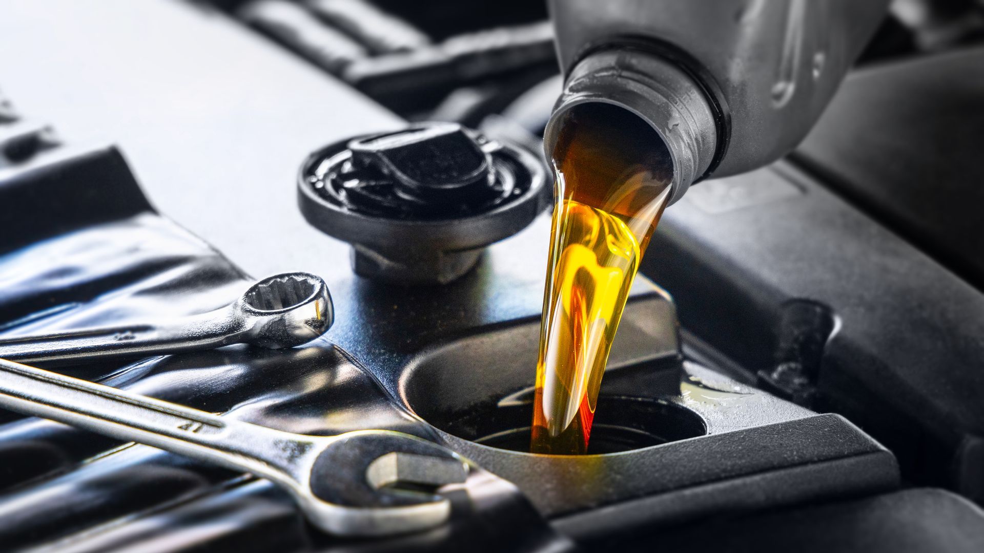 Pouring motor oil for motor vehicles from a gray bottle into the engine.