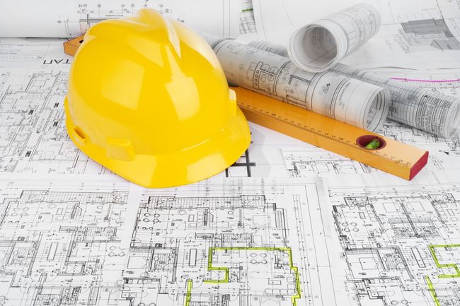 Casque jaune, niveau et plans architecturaux enroulés.