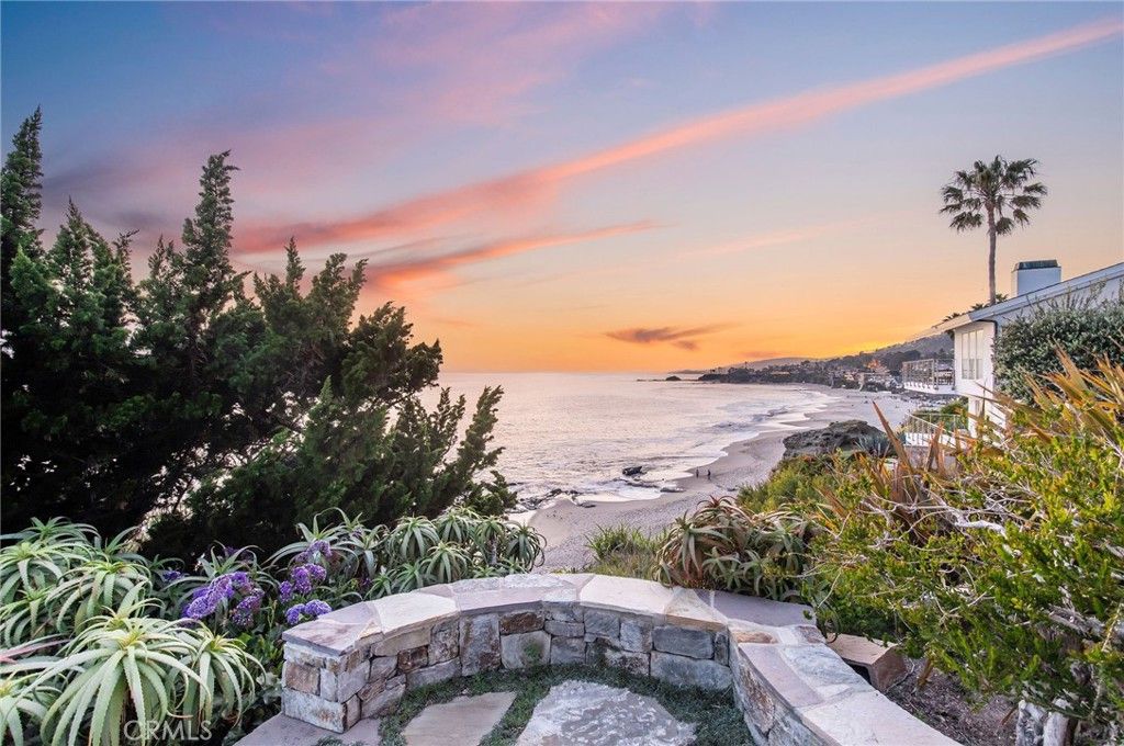 A view of the ocean from a stone wall with a sunset in the background.