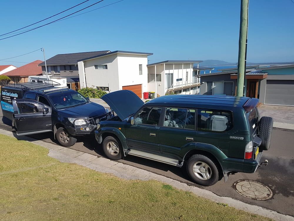 Two Cars Are Parked on the Side of the Road With Their Hoods Open — South Coast Locksmiths in Thirroul, NSW