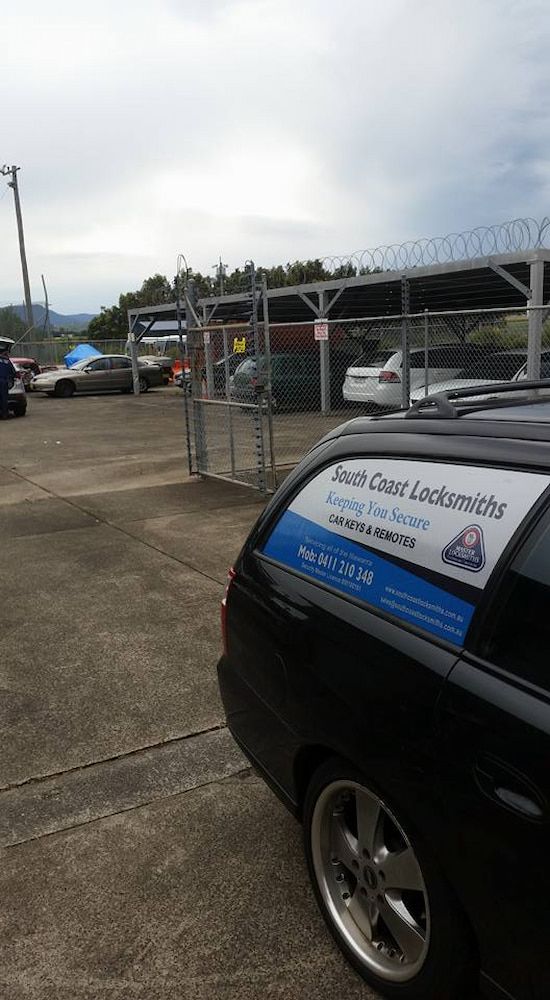 A Black Car is Parked in a Parking Lot Next to a Barbed Wire Fence — South Coast Locksmiths in Warrawong, NSW