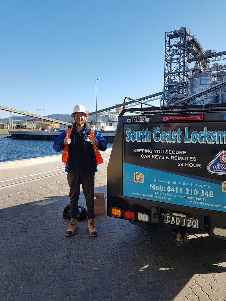 A Man is Standing in Front of a South Coast Locksmith Truck — South Coast Locksmiths in Albion Park, NSW