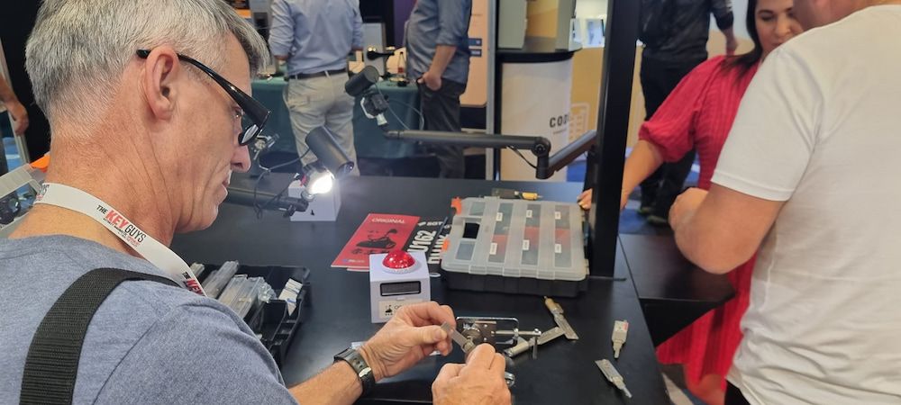 A Man is Sitting at a Table Working on a Piece of Equipment — South Coast Locksmiths in Fairy Meadow, NSW