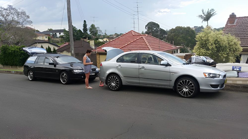 A Woman is Standing Next to a Silver Car on the Side of the Road — South Coast Locksmiths in Austinmer, NSW