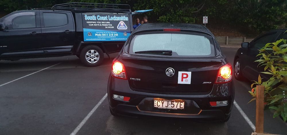 A Black Car is Parked in a Parking Lot Next to a Truck — South Coast Locksmiths in Corrimal, NSW