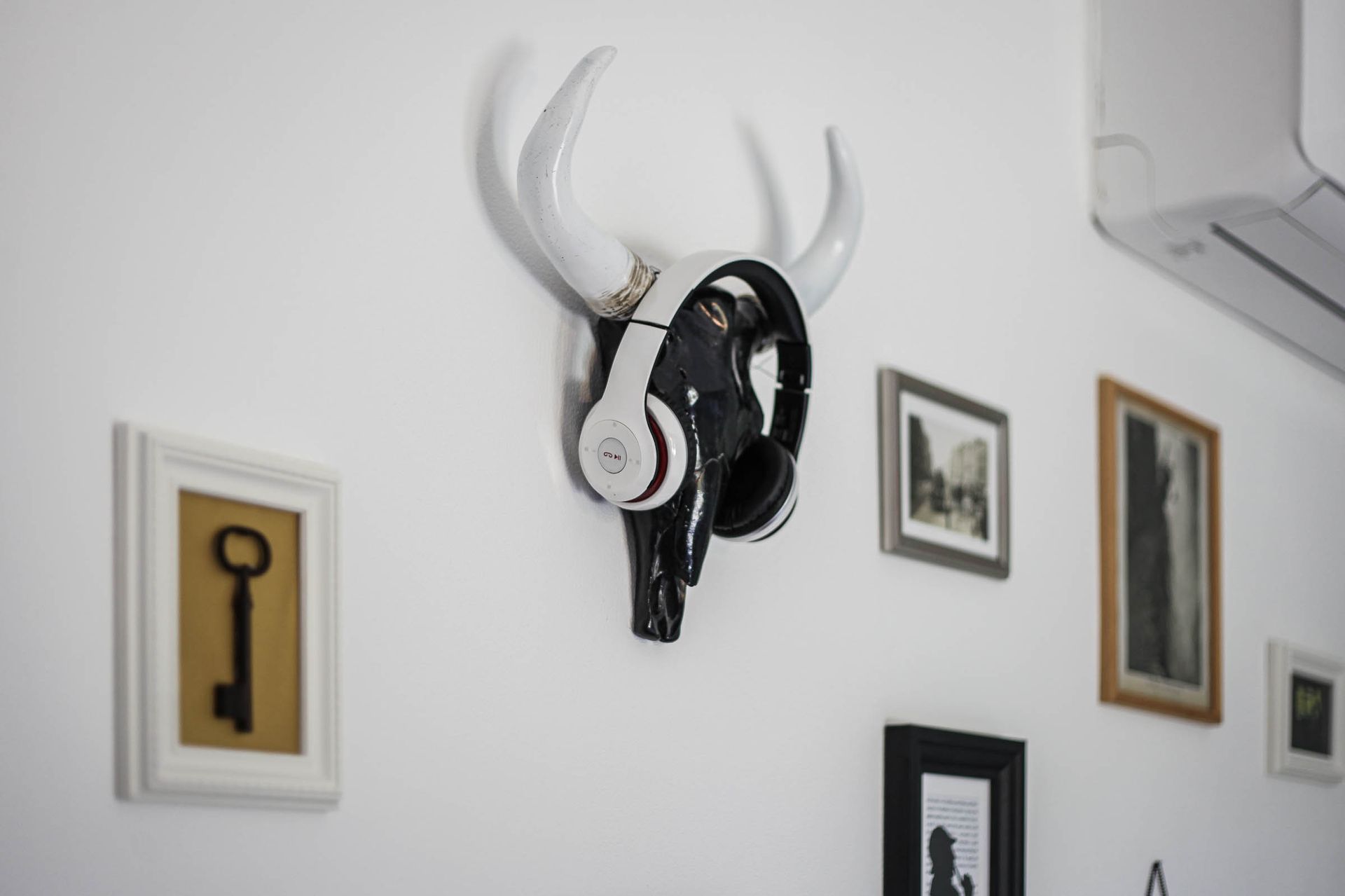 Wall-mounted black bull head with white horns and headphones among framed wall art