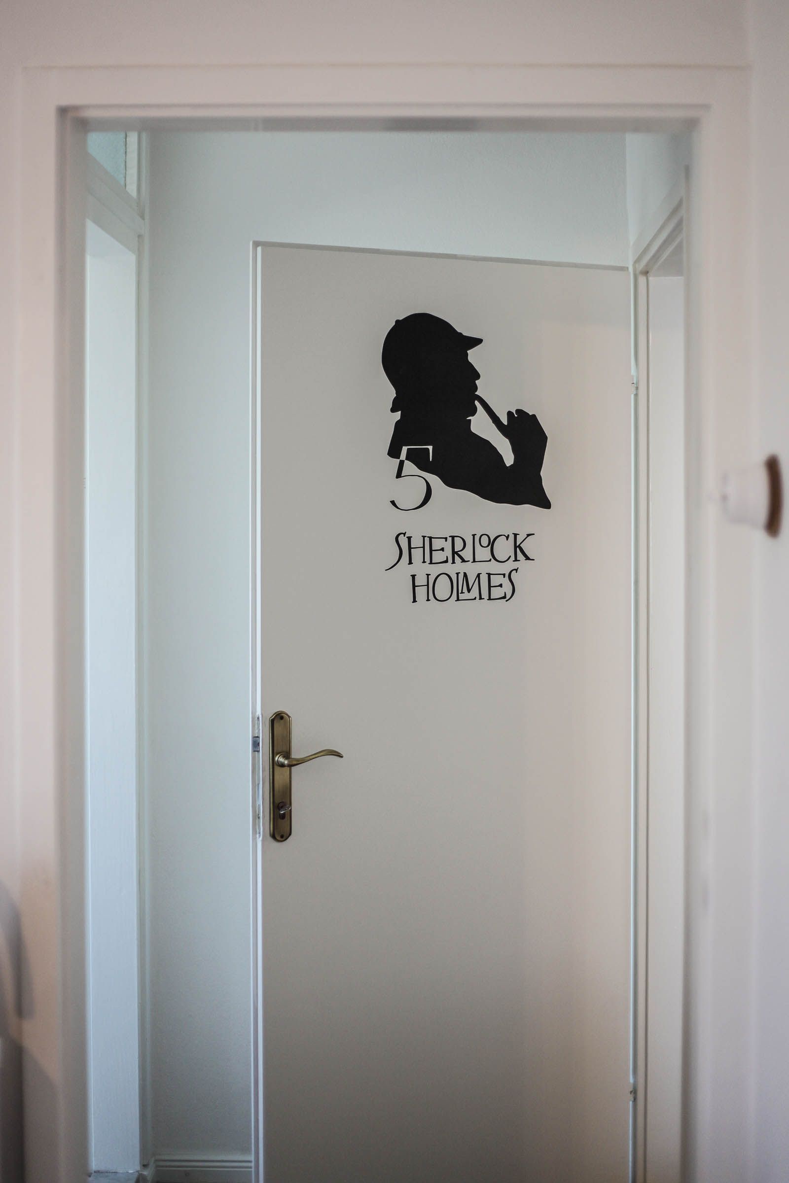Open white door with black silhouette decal in a hallway frame