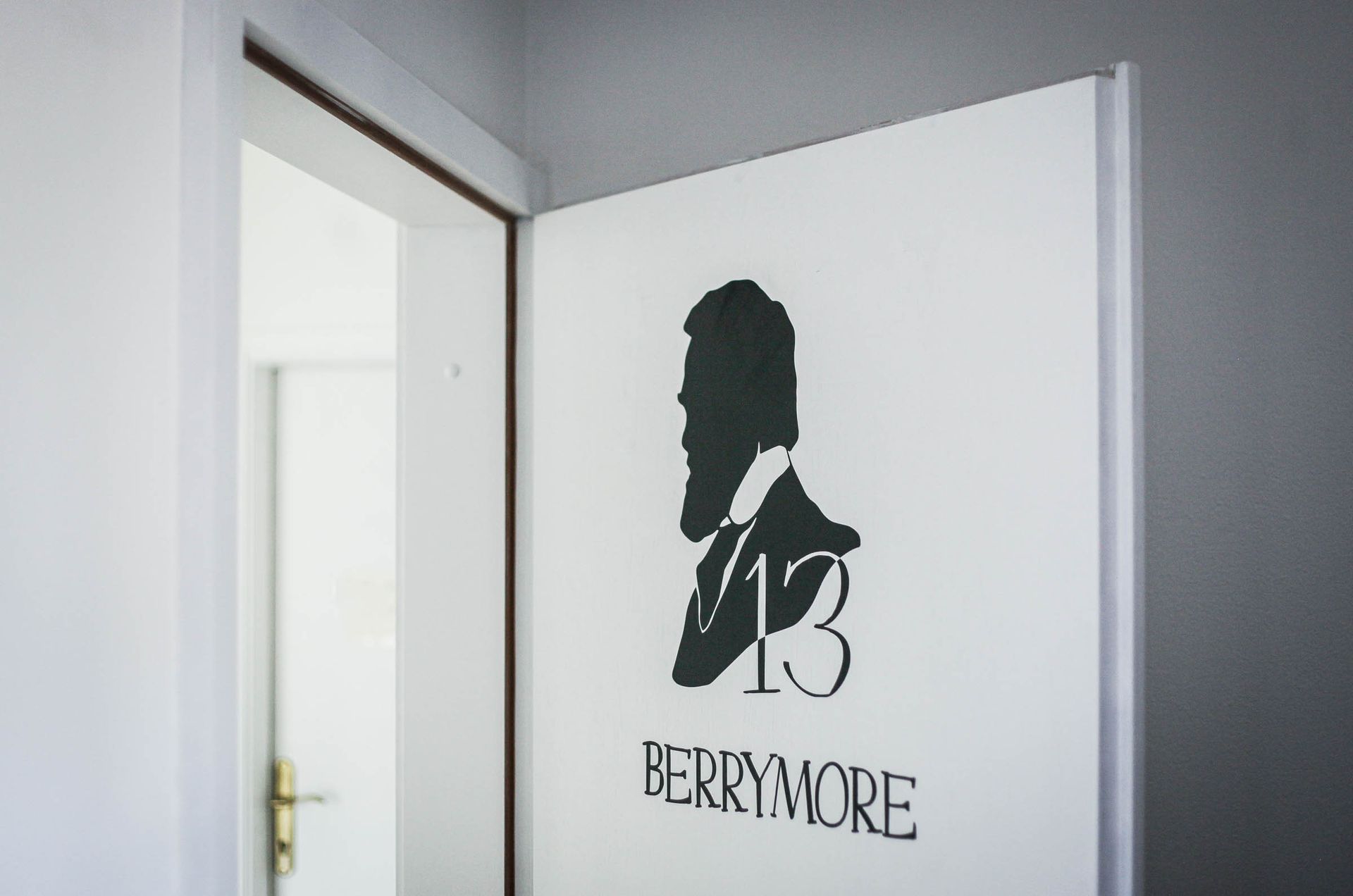 White door with black “BERYMORE” logo and silhouette, partly open in a hallway.
