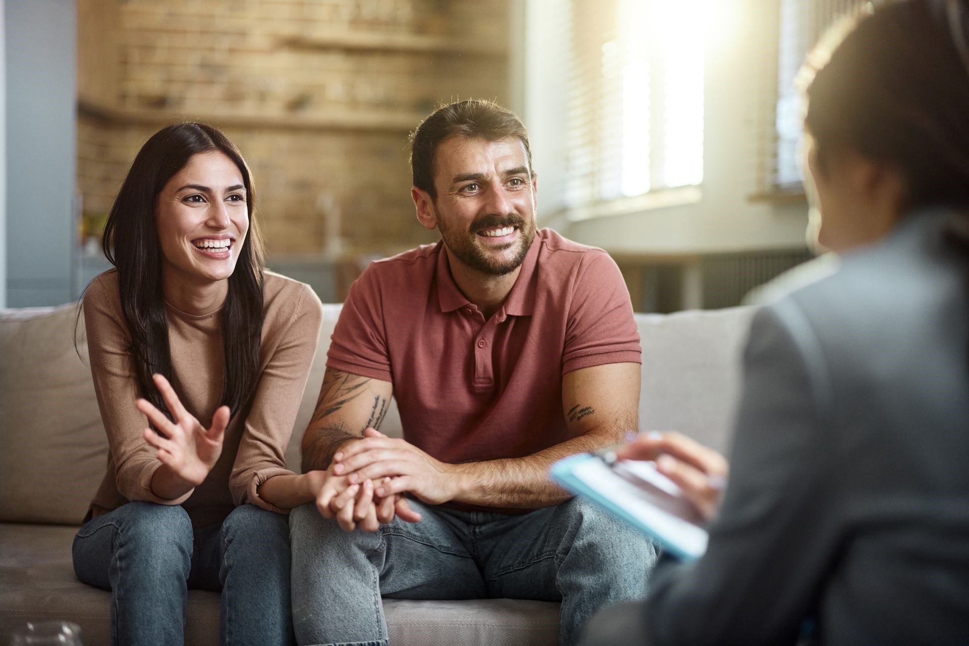 Smiling couple talking with a counselor in a bright living room during a session Smiling couple talking with a counselor in a bright living room during a session