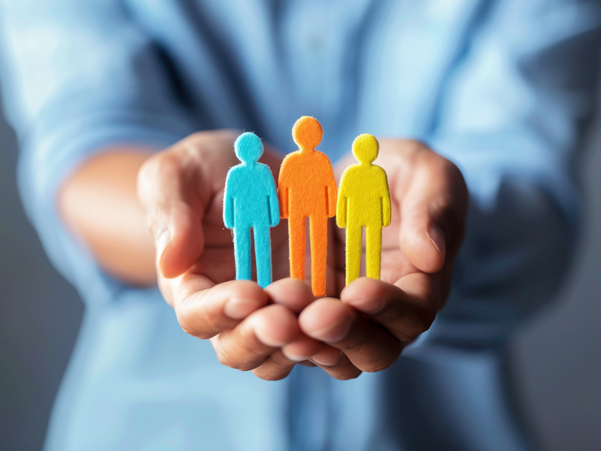 A person is holding a cutout of three people in their hands