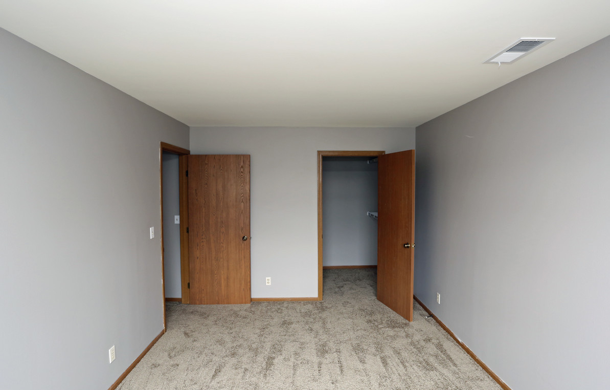 An empty bedroom with a carpeted floor and gray walls.