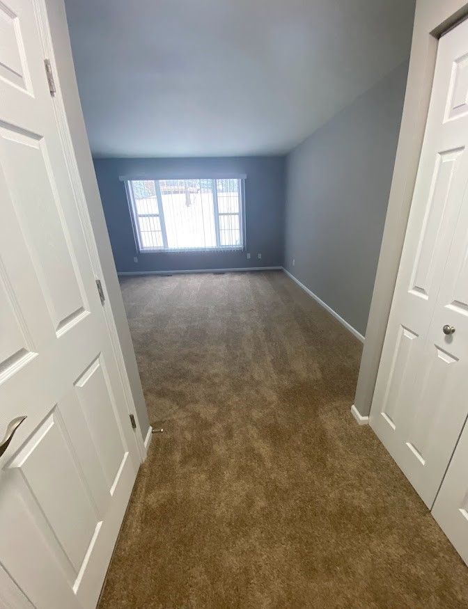 A hallway leading to a living room with a large window.