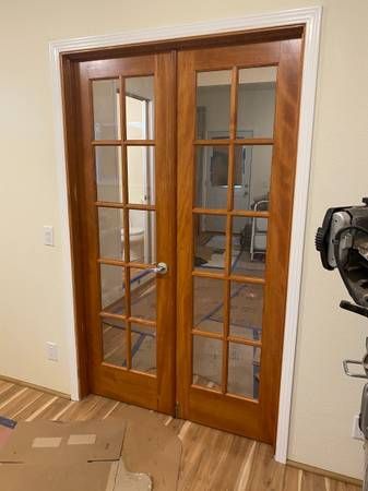 A pair of wooden french doors with glass in a room.