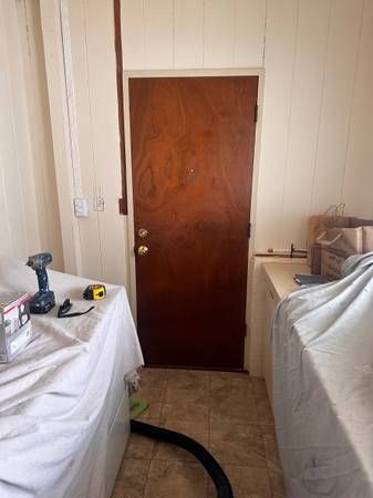 A laundry room with a wooden door and a vacuum cleaner.