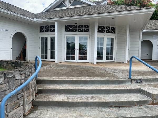 A white house with a blue railing and stairs leading up to it.