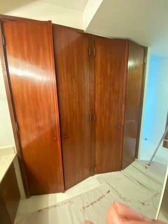 A person is standing in a room with a lot of wooden doors.