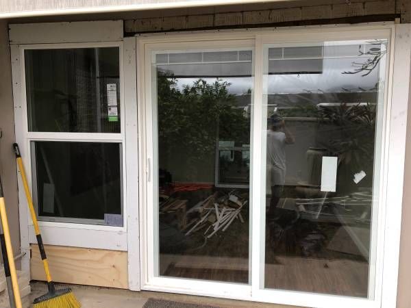 A white sliding glass door is being installed on a house.