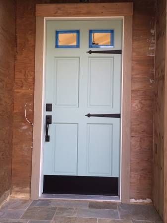 A light blue door with a black handle is sitting on a tiled floor.