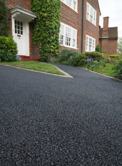 A new asphalt driveway and walk leading up to a brick home with lush green landscaping in new albany ohio
