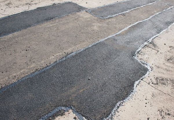 Asphalt parking lot with large patched area.