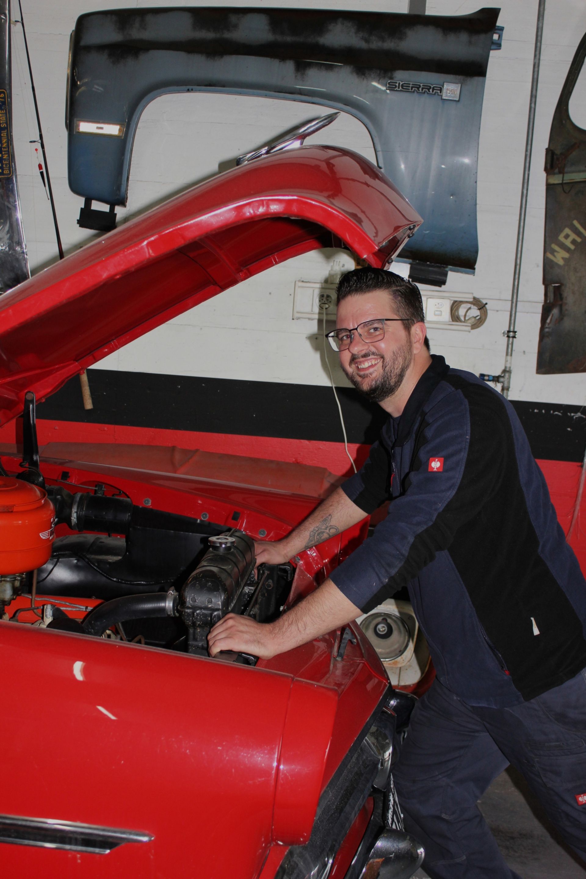 Ein Mann arbeitet in einer Garage an einem Automotor.
