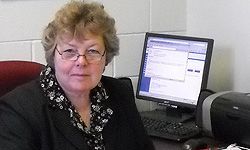 A woman is sitting at a desk in front of a computer.
