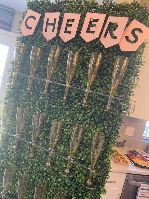 Champagne glass display on a green hedge wall with 