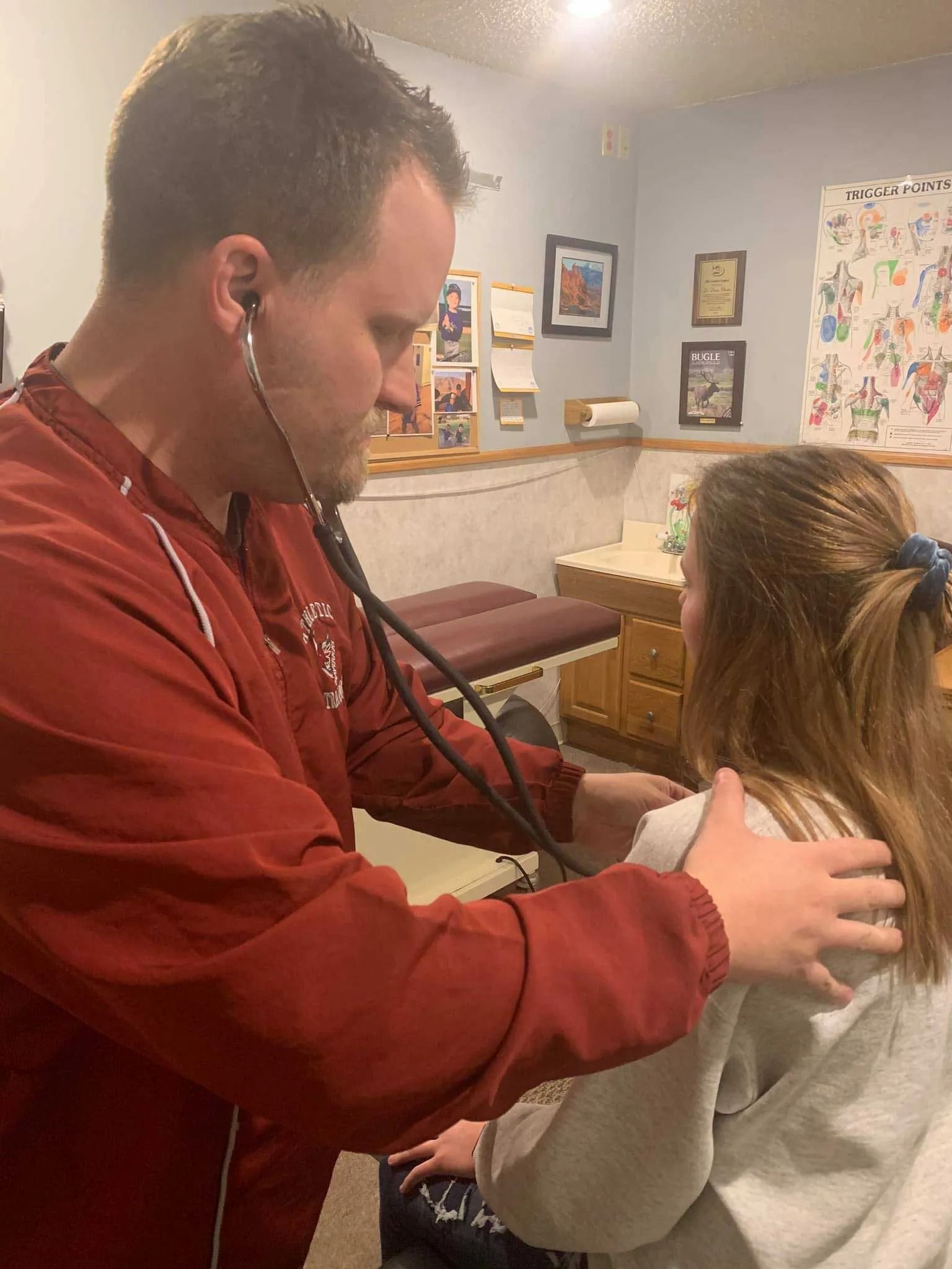 A doctor is examining a young girl with a stethoscope.