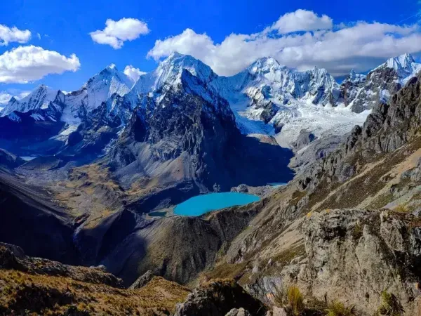 Snowy mountain peaks above a turquoise alpine lake under a bright blue sky