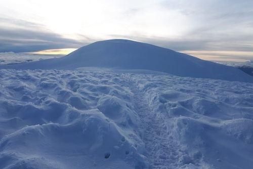Snow-covered landscape with a large mountain under a cloudy sky