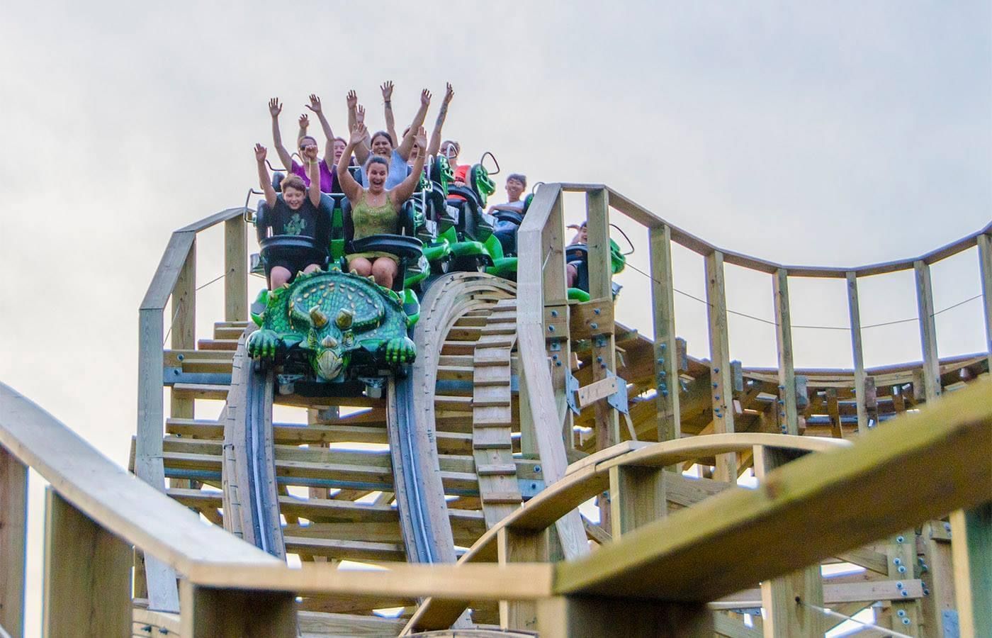 A group of people are riding a roller coaster at an amusement park.