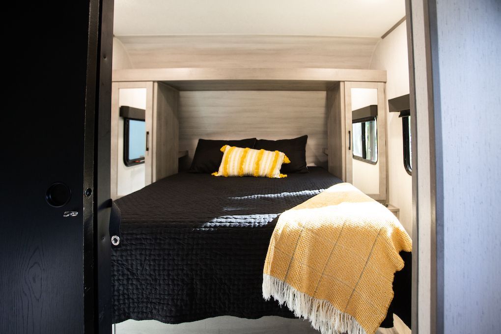 A bedroom in a rv with a bed and a yellow blanket.