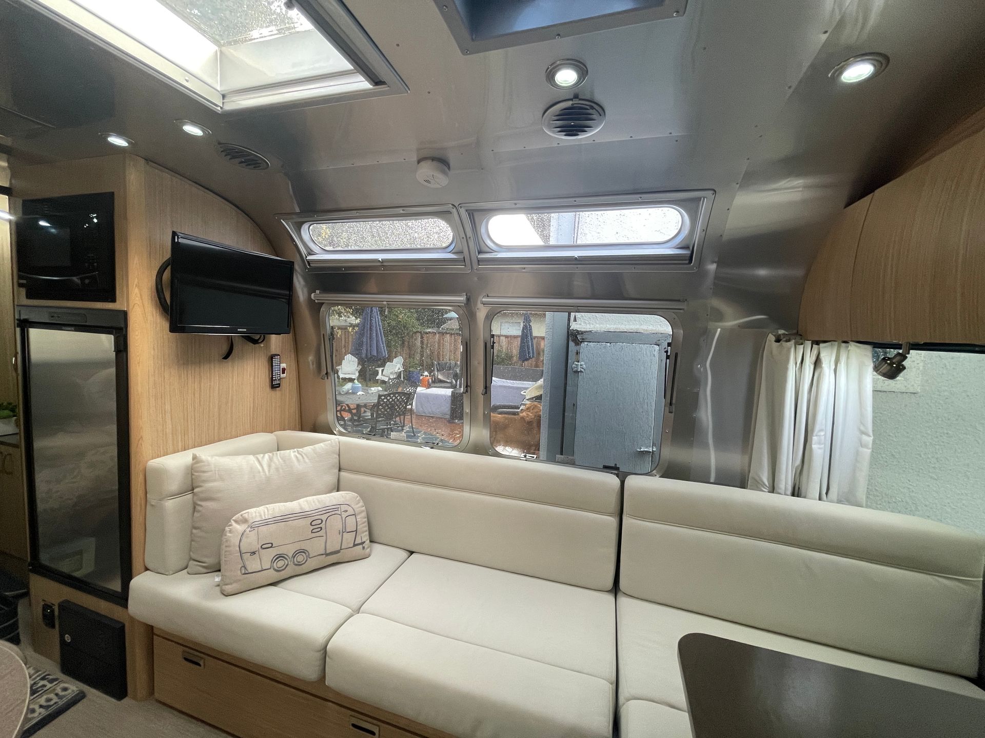 A living room in an airstream trailer with a couch and a television.