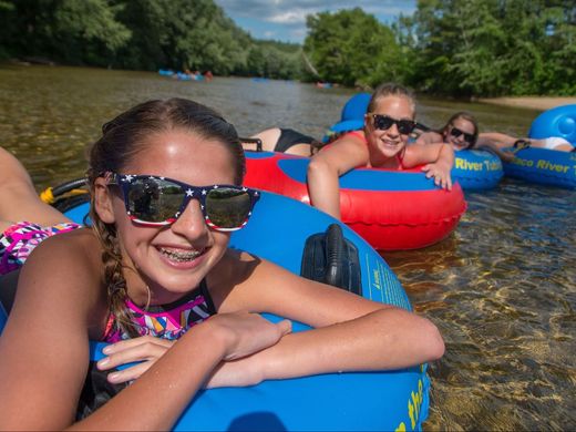 kids floating in tubes on the river in a shallow area by the beach