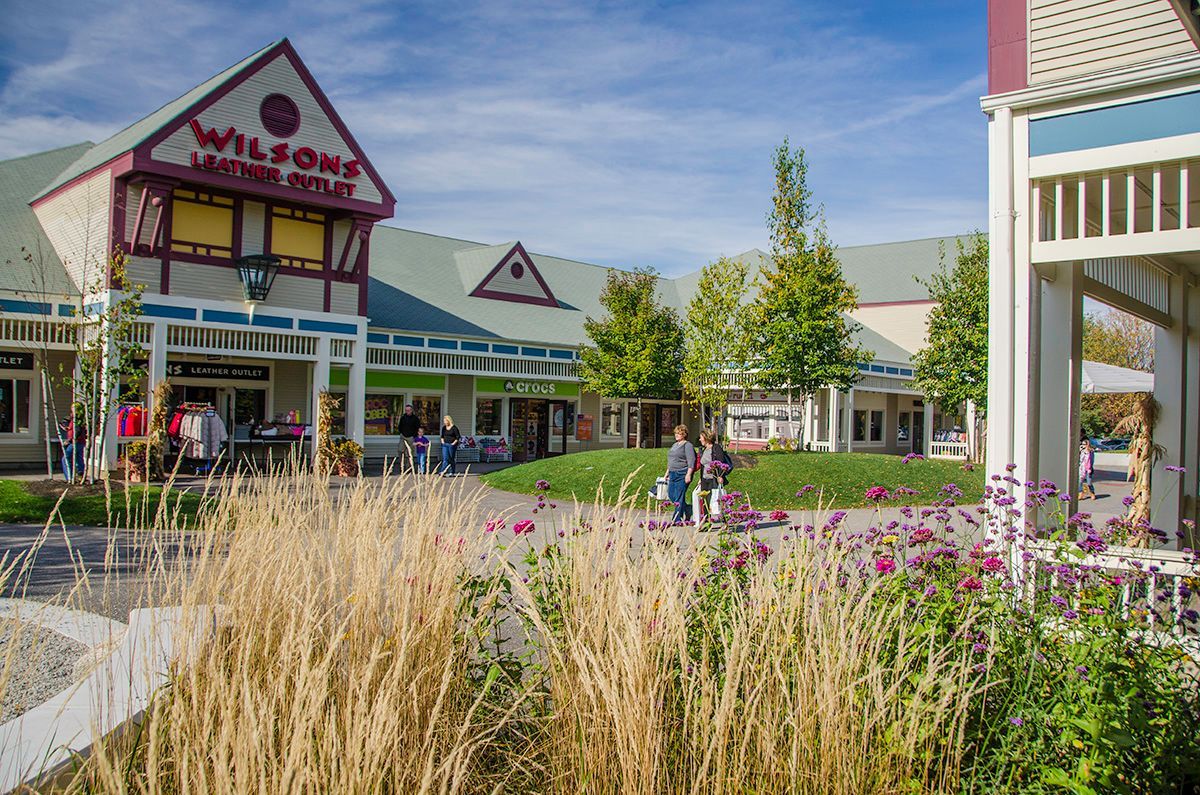 A group of people are walking in front of a shopping mall.