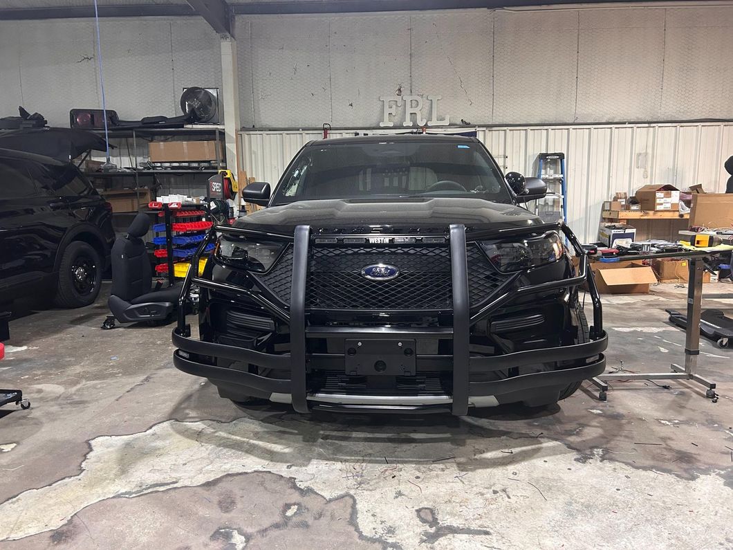 Black police SUV with a push bar, parked inside a garage.