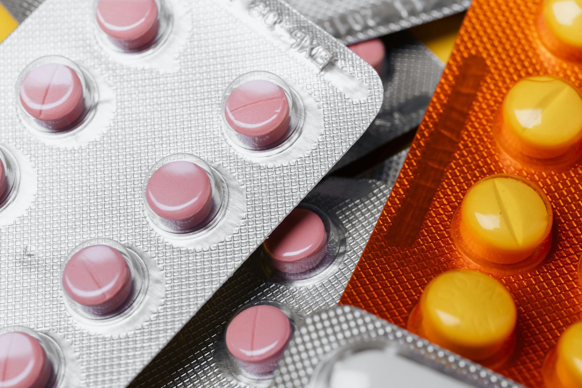 Pink and yellow pills in blister packs, for medical use.