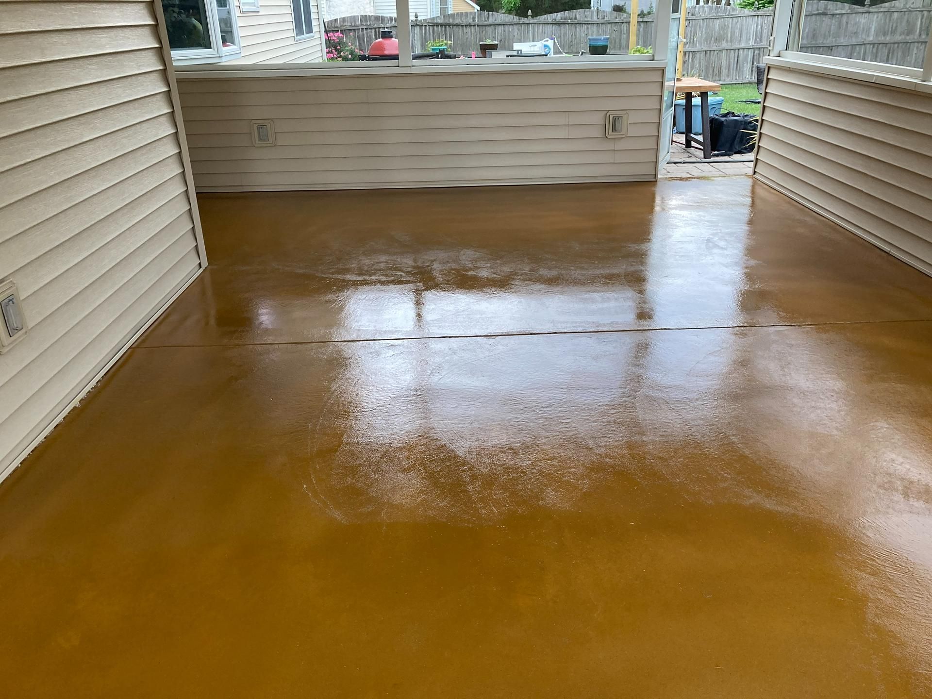 Covered patio with a freshly coated glossy brown floor and beige siding on both sides