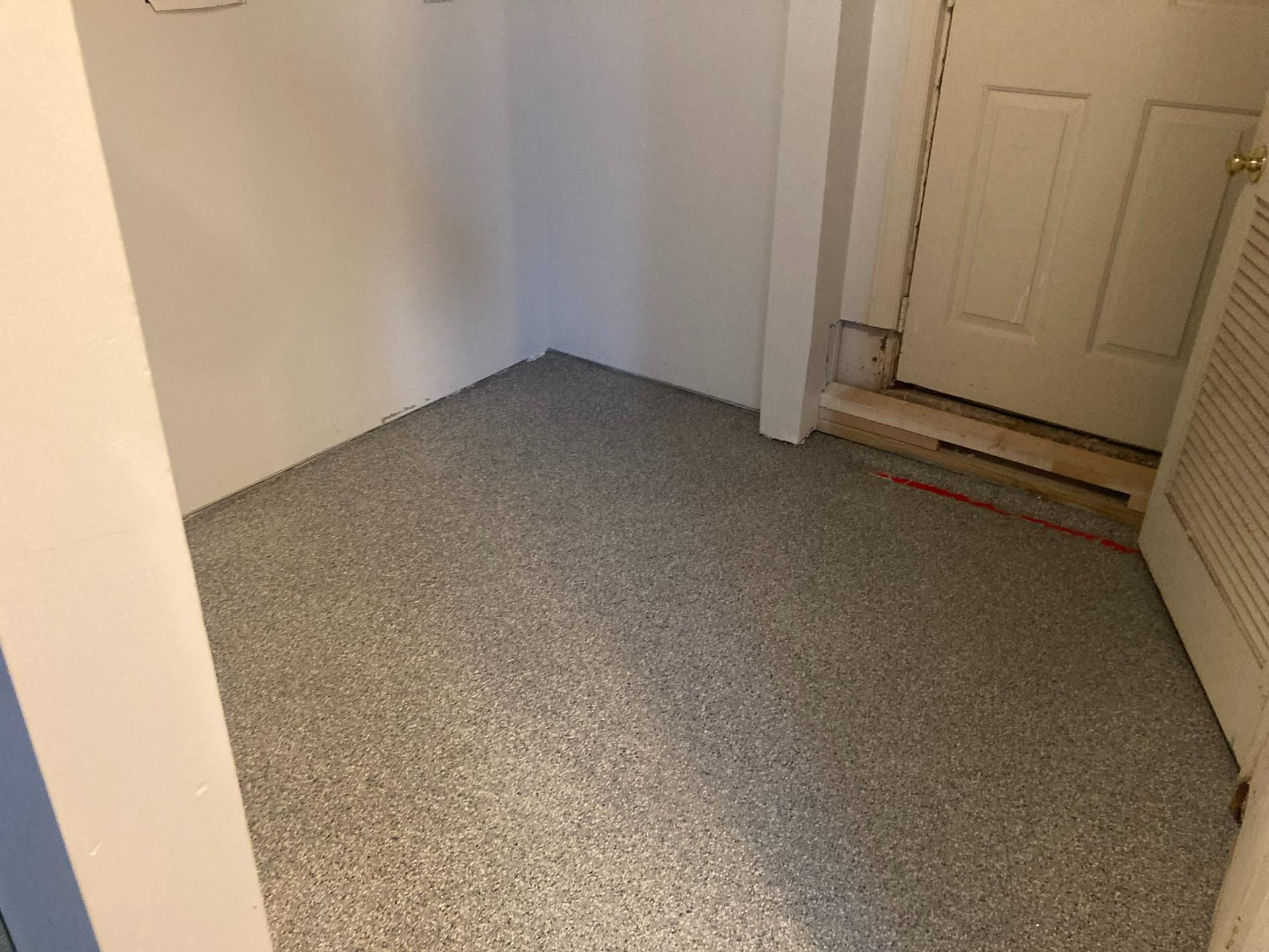 Small empty hallway with gray carpet and white walls near a front door.