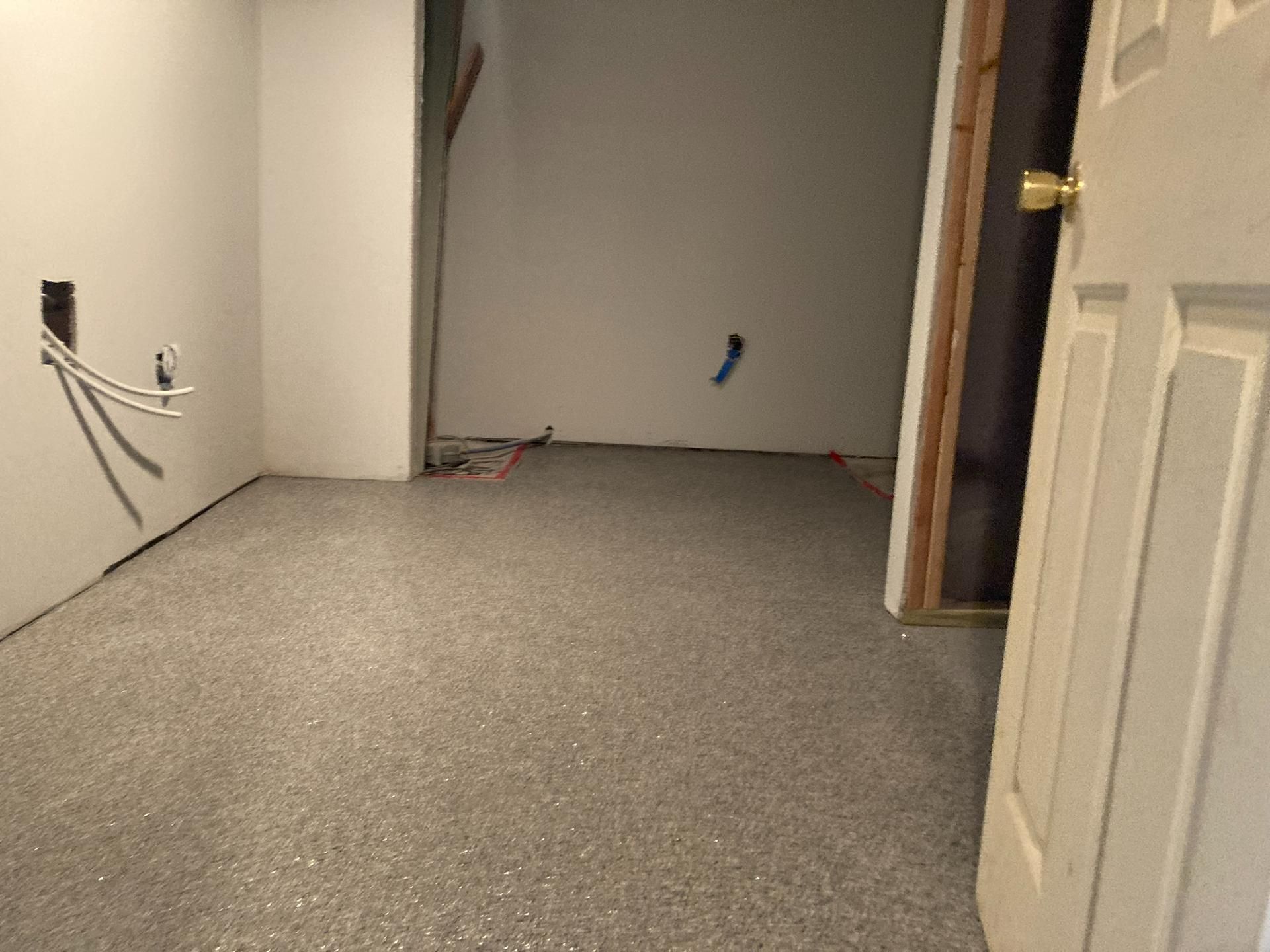 Empty carpeted room under renovation with exposed cables and unfinished walls
