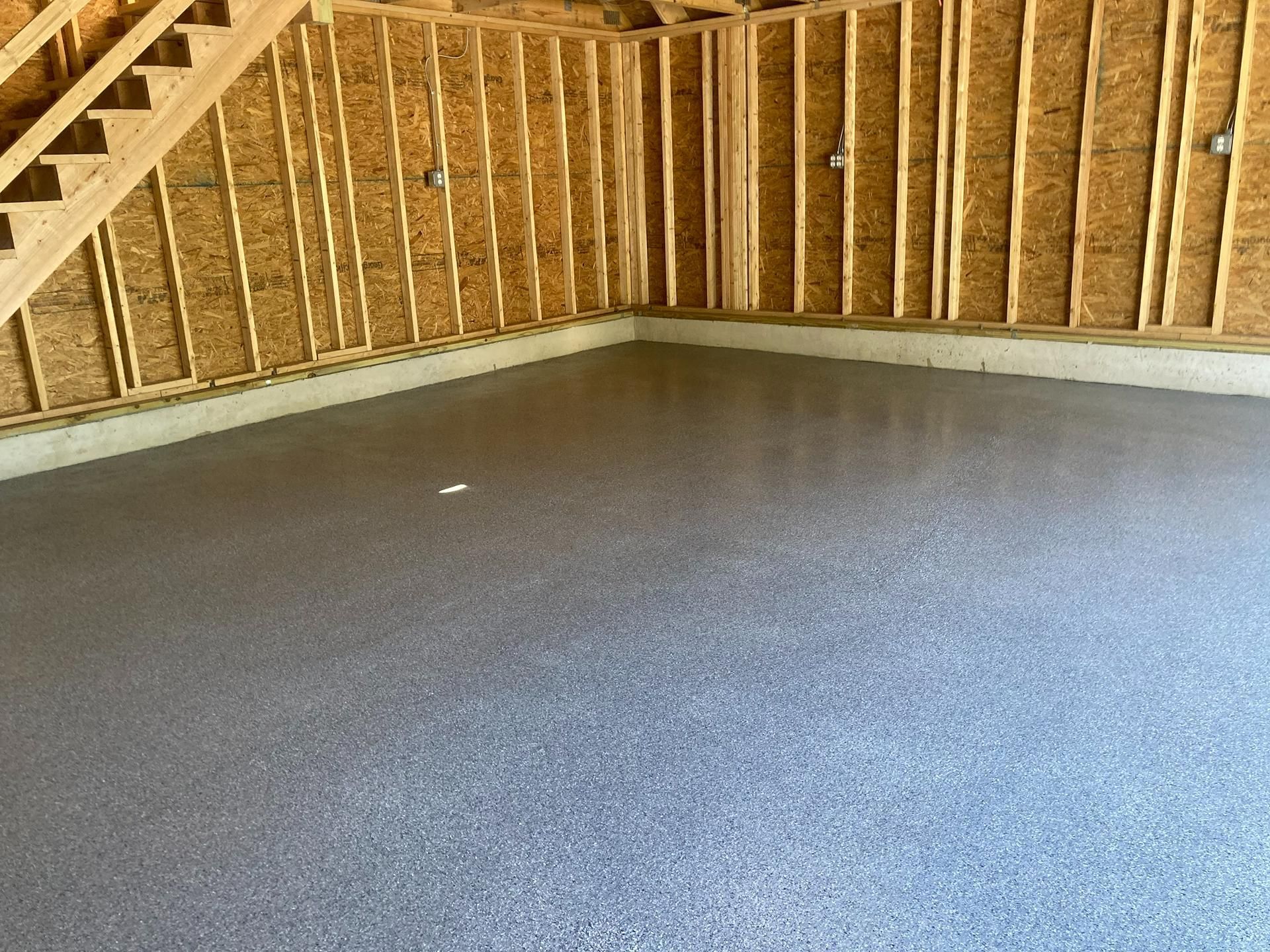 Empty unfinished room with exposed wooden framing and a gray subfloor