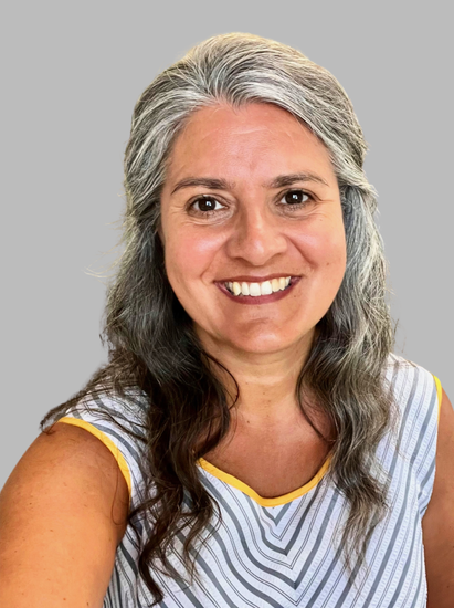A woman with gray hair is smiling and wearing a striped shirt.