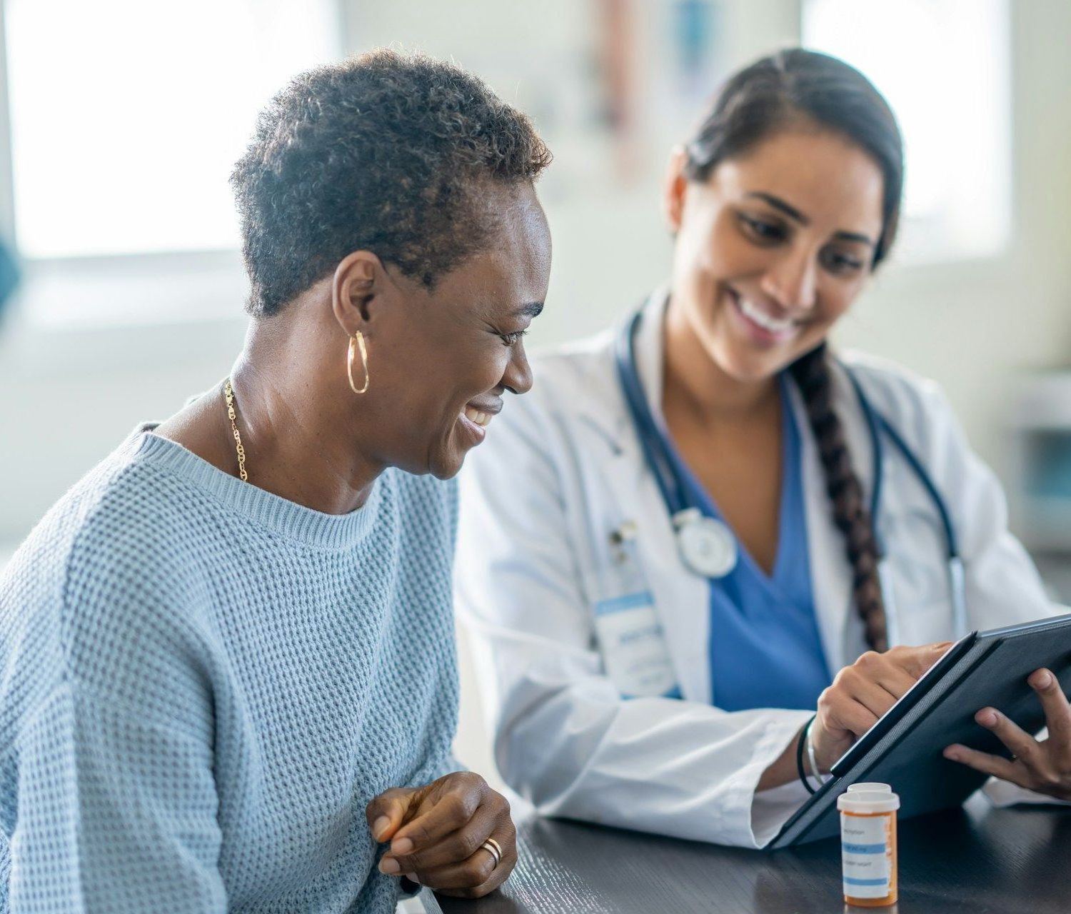 A doctor is talking to a patient while looking at a tablet.