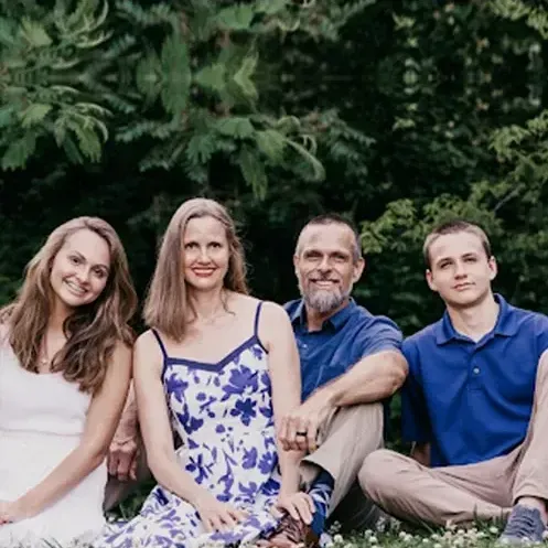 A group of people are posing for a picture while sitting in the grass.
