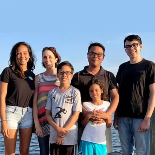 A group of people are posing for a picture in front of a body of water.