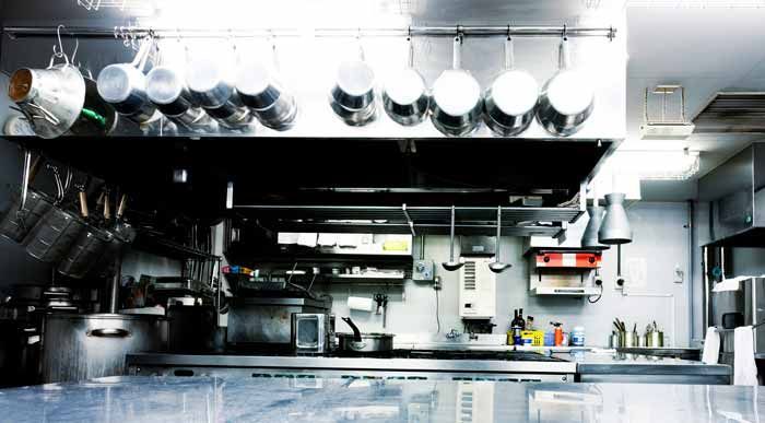 Una cocina con muchas ollas y sartenes colgando del techo.