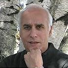 Man with gray hair, hand on chin, looking at the viewer.