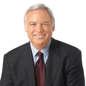 Man in a suit smiles at the camera, with a dark jacket, red tie, and light blue shirt.